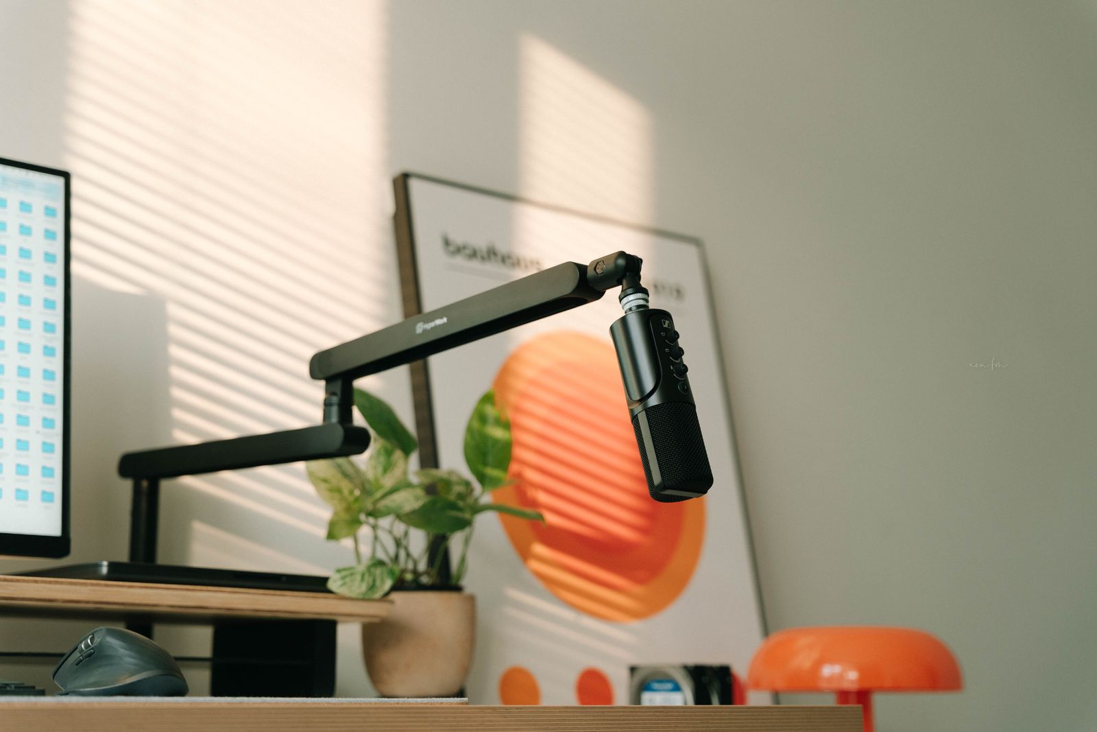 Ein Desktop-Mikrofon an einem Galgenarm über einem aufgeräumten Home-Office-Schreibtisch, ein typisches Setup für Spracherkennung